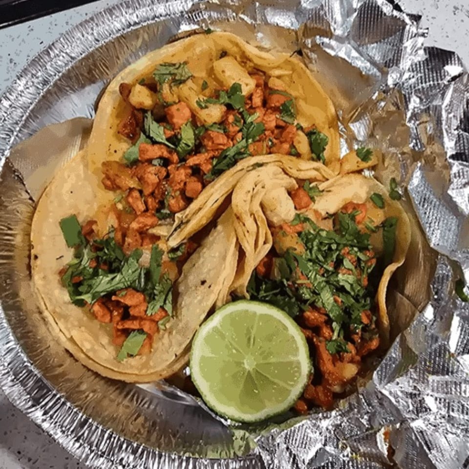 Three Casa Grande Cantina & Grill Mexican tacos with meat, cilantro, and a lime wedge in foil.
