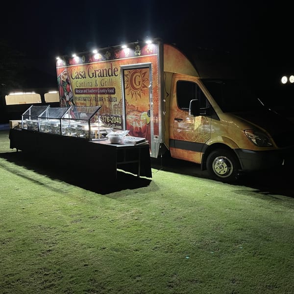 Casa Grande Cantina & Grill food truck and buffet setup on grass at night.