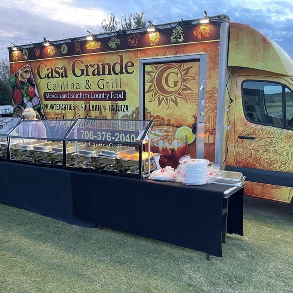 Casa Grande Cantina & Grill food truck with a buffet setup and a woman serving food.